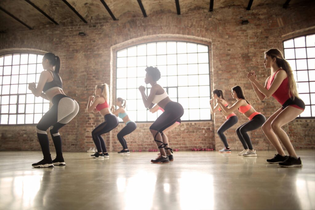 pexels-photo-3775566-3775566 Women participating in a group fitness class performing squats in an industrial-style studio.