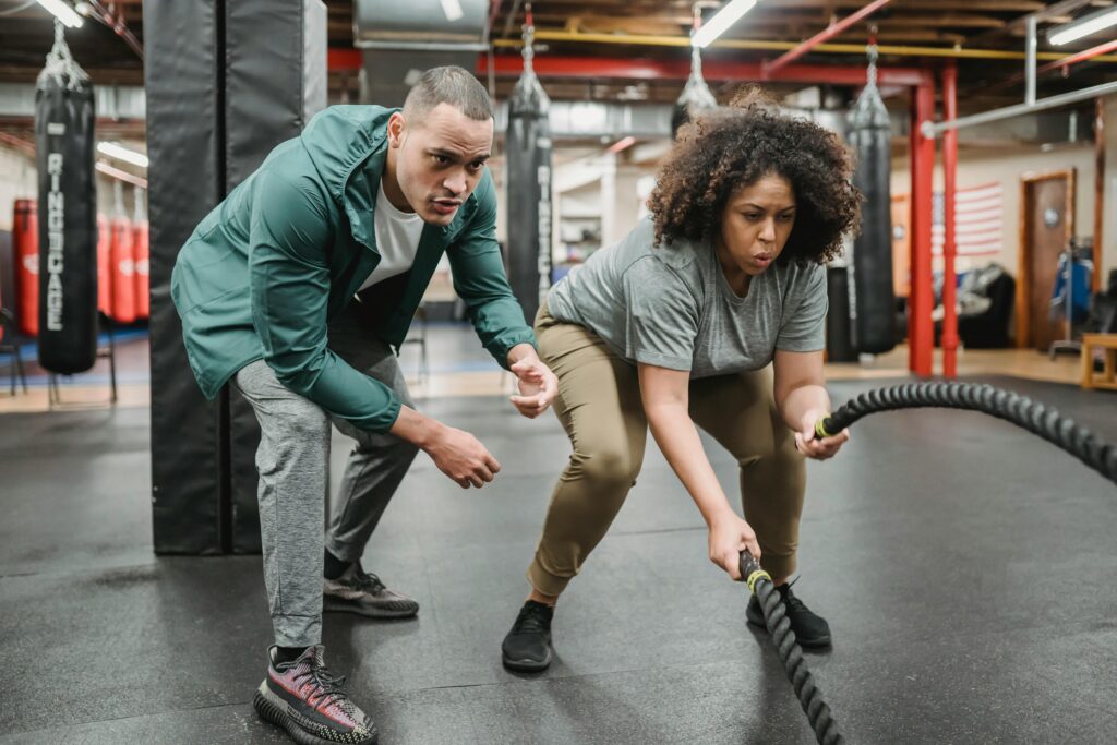pexels-photo-6455791-6455791 A dedicated woman focuses on battle rope training, guided by her fitness coach.