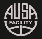 Man walking in gym with colorful ball near AUSA Facility wall, wearing sporty outfit.